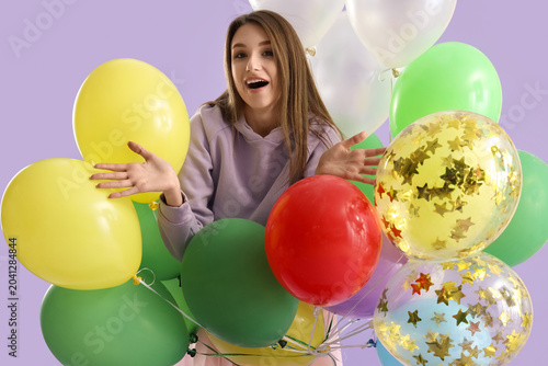 Tableau sur toile Young woman with colorful balloons on lilac background