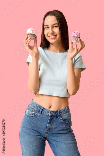 Young woman with sweet cupcakes on pink background. Valentine's Day celebration