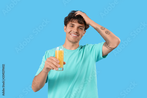 Young man with glass of orange juice on blue background