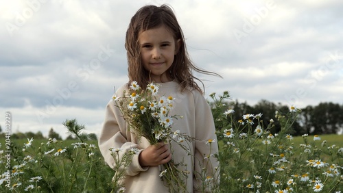 Εκτύπωση καμβά Young girl smiling and holding a freshly picked bouquet of white chamomile flowe