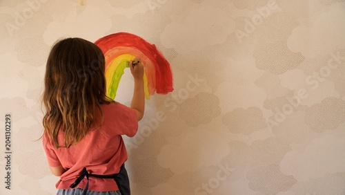 Φωτογραφία Young child expressing creativity by painting a vibrant rainbow on a cloudy patt