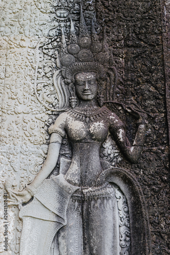 Naklejka premium Apsara dancer bas-relief carving on the walls of Angkor Wat temple complex, Siem Reap, Cambodia. These celestial dancers are a common motif in Khmer art.