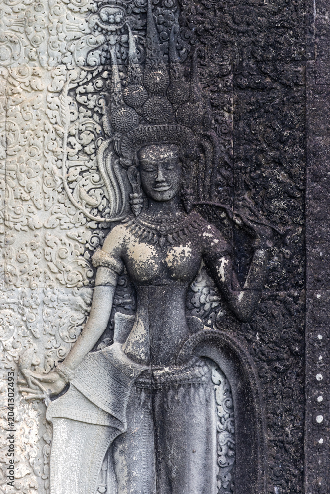 Fototapeta premium Apsara dancer carving on the walls of Angkor Wat temple complex in Siem Reap, Cambodia. These celestial dancers are depicted in ancient Khmer art.