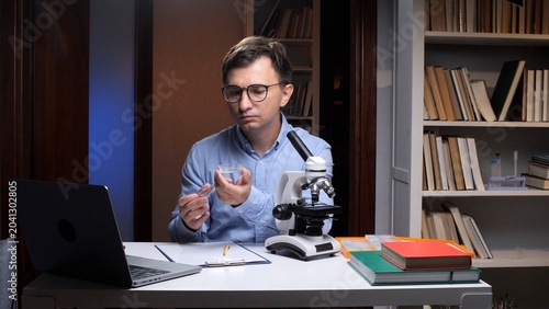 Slika na platnu Focused researcher holding and observing a petri dish with liquid, conducting sc
