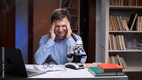 Fotografie Male scientist feeling intense head pain and exhaustion while working late at hi