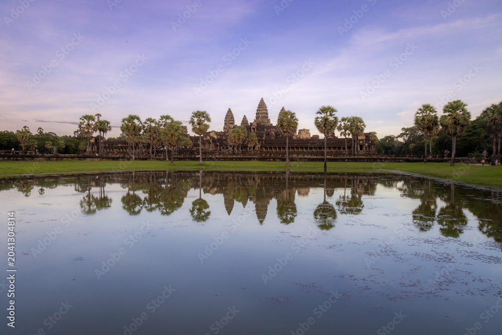Naklejka premium Angkor Wat temple complex in Siem Reap, Cambodia, reflected in a pond at sunset. This iconic UNESCO World Heritage site is a breathtaking example of Khmer architecture.