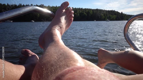 Stockholm, Sweden Feet and legs basking in the sun on a small motorboat in Lake Malaren on a sunny summer day. 