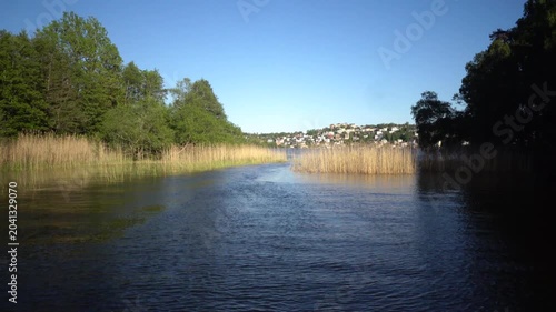 Stockholm, Sweden A picturesque view of a narrow grassy passage on Lake Malaren from a moving boat. 