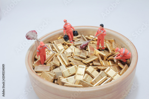 Miniature workers cleaning piles of gold