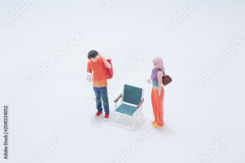 Miniature couple near empty chair scene