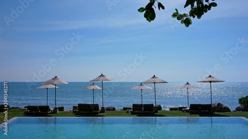 Swimming pool with umbrella and chair on sea view background
