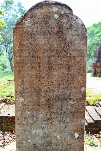 Фотография Ancient stone stele with carved old Cham script text inscription close up at My