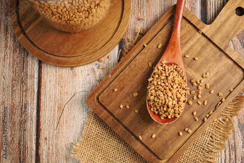 Tableau sur toile Fenugreek seeds on wooden spoon and board in kitchen