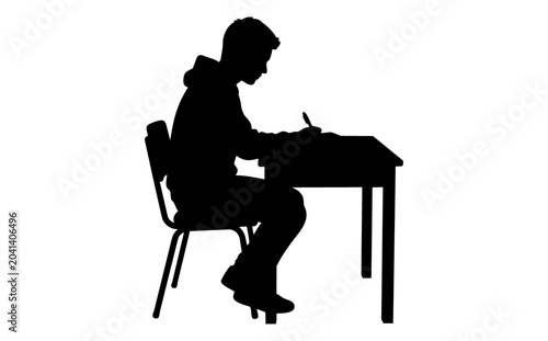 Silhouette of a focused young male student wearing a hoodie diligently writing at a desk with a pen captured in a side profile against a stark white background symbolizing