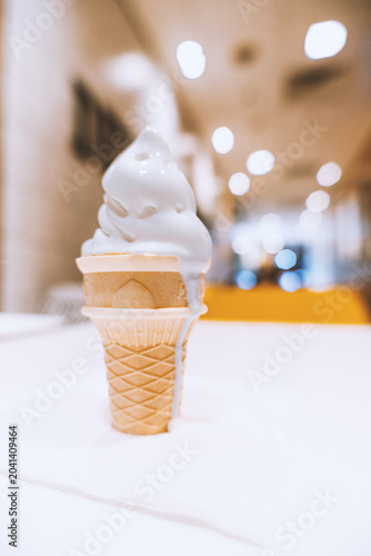 Soft Serve Ice Cream in Waffle Cone on White Table in Modern Café with Bokeh Background