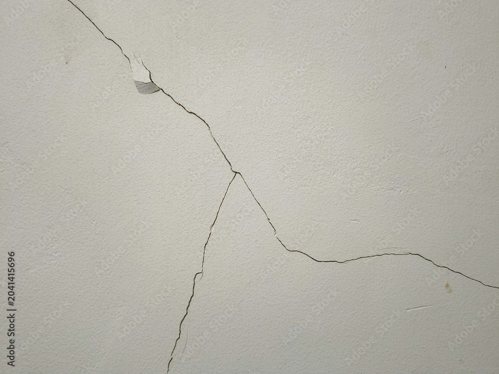 Fotografie Cracks on a white wall surface indicating structural wear or plaster damage