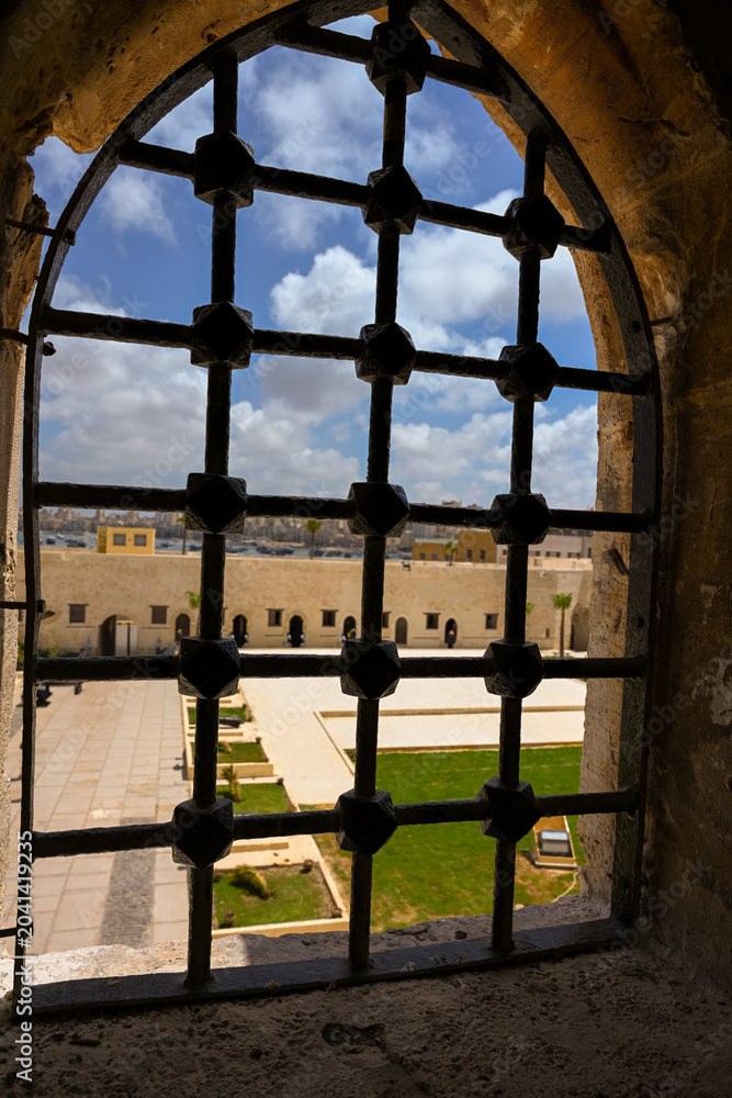 Fototapeta premium View of fortress grounds through an iron-barred fortified window at Qaitbay Citadel