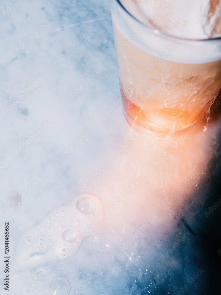 Fototapeta premium Light colored marble background with copy space next to a cold glass of iced coffee for cafe menu design, hospitality branding and summer beverage advertising