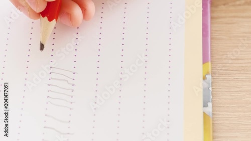 small hand preschool child diligently draws elements with pencil in notebook on table close-up, learning to write, spiral college block, student writing supplies, back to school