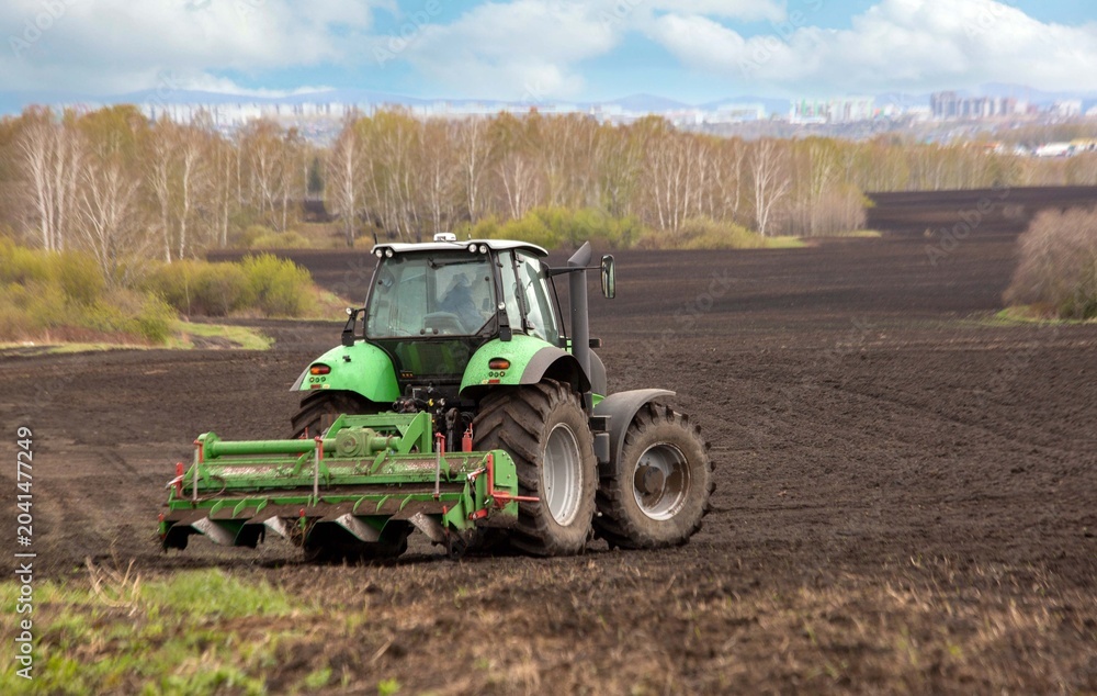 Fototapeta premium A tractor plowing a field in spring. Agricultural work, farming.