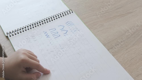 Close up preschool kid hand writing letter elements in notebook, practicing handwriting strokes, early literacy and school preparation concept, Developing fine motor skills and hand-eye coordination