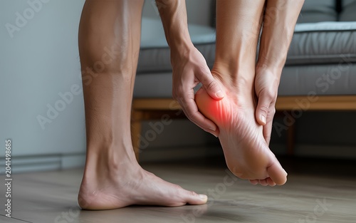 Person holding foot heel with red pain symbol plantar fasciitis heel spur discomfort.