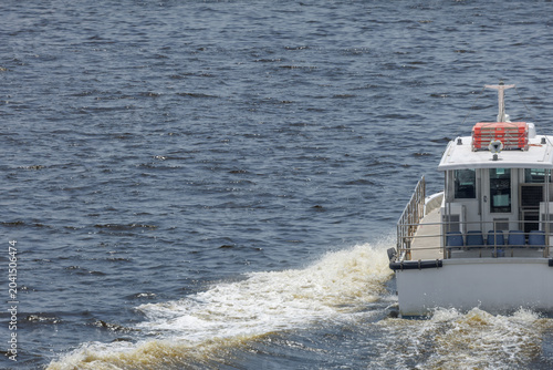 Canvas Print Small passenger vessel heading out through choppy open water, leaving a frothy, widening wake that merges with sunlit surface waves
