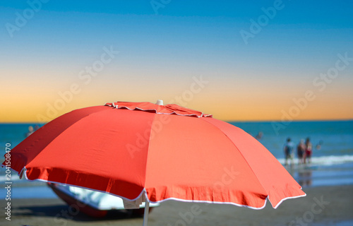 The setting sun paints the sky behind the open umbrellas