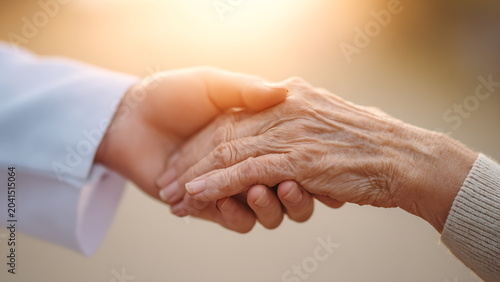 a young doctor gently holding an elderly patient's hands