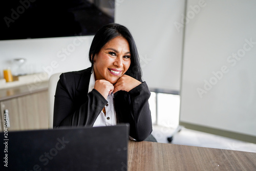 Latina businesswoman smiling in modern office environment