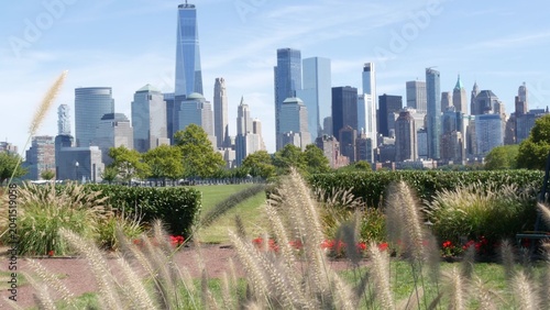 New York City Manhattan Downtown Financial District skyline, World Trade Center tower from New Jersey Liberty state park, United States. Green grass lawn, flowers and skyscraper buildings cityscape