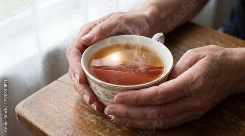 Surreal Close-up of Elderly Hands Holding Teacup with Desert Landscape Inside