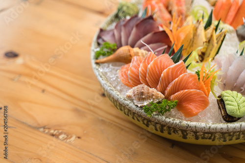 A beautifully arranged Japanese sashimi platter with fresh salmon, and shellfish on ice, garnished with vegetables., tuna, white fish