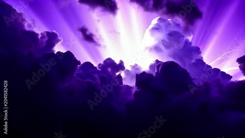 Majestic, dramatic sunbeams breaking through thick, dark purple storm clouds, creating a spiritual and atmospheric scene.
