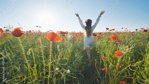 Fotografie Carefree woman wandering amid red poppy blooms, basking in golden sunlight and e