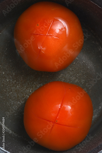 Canvas-taulu A top view of two fresh red tomatoes with a cross cut on top placed inside a dar
