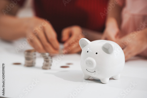 Tableau sur toile A young mother is setting a good example, teaching her little daughter about financial management and saving money