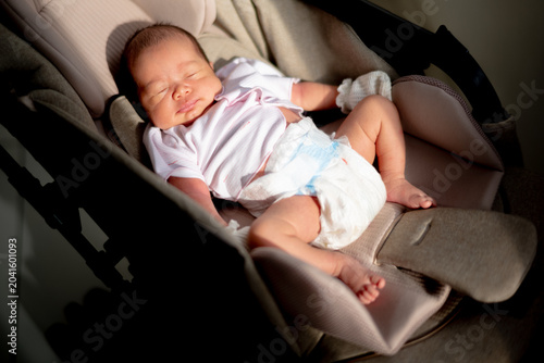 Fotografie Peaceful newborn baby sleeping in a stroller bassinet with warm dramatic sunlight shining across