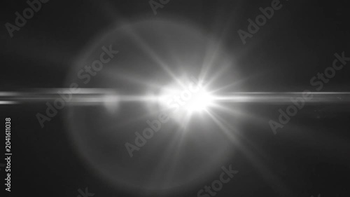 Bright light shines with lens flare on dark background creating a dramatic effect with technology