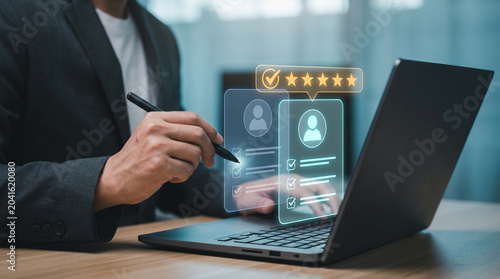 Holographic Employee Evaluation Interface with Star Rating and Profile Cards Appears Above Laptop as Manager Reviews Candidate Assessments to Rate Staff Competency, Compare Team Members