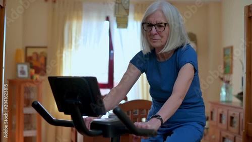 Senior Woman Exercising On Stationary Bike At Home For Healthy Active Aging  