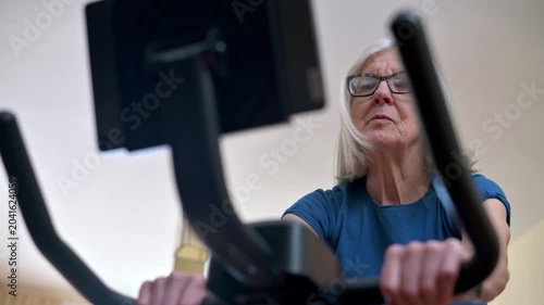 Older woman focused on a home workout using a stationary exercise bike  