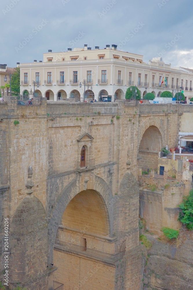 Fototapeta premium Close-up view of Puente Nuevo bridge stone arch structure with historic yellow building and town square — detailed 18th century masonry of iconic Ronda landmark, Andalusia, Spain