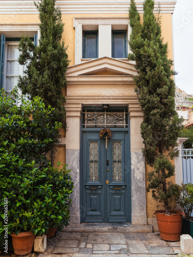 Traditional May 1st flower wreath hanging on an ornate green vintage door in the historic Plaka neighborhood of Athens.