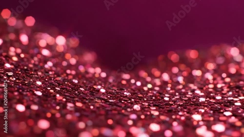 Shimmering close-up of pink glitter in soft focus reflecting light and creating a sparkling effect