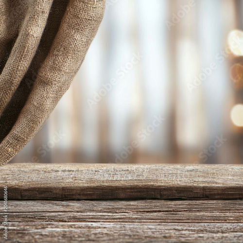 Rustic wooden table with draped burlap fabric and blurred warm bokeh lights background