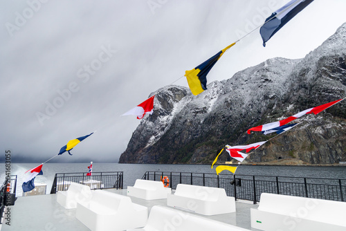 Foto An empty upper deck of a tour ferry in fjords with nautical flags blowing in the wind