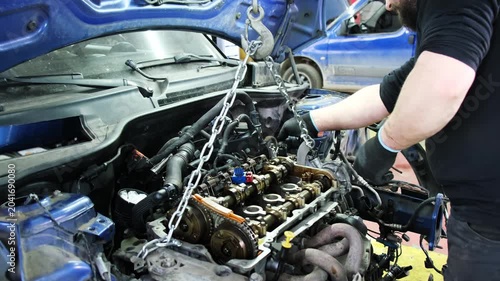 Specialist reviews reliability of chain and inspects engine. Technician in gloves performs comprehensive repair of system standing in front of car