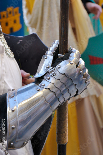 Photos Close‑up of a medieval armored gauntlet gripping a pole weapon, during an outdoo