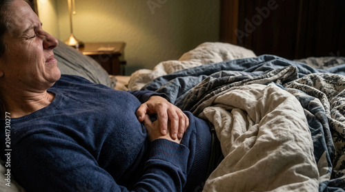 Woman Suffering from Abdominal Pain Resting In Bed And Clutching Her Stomach